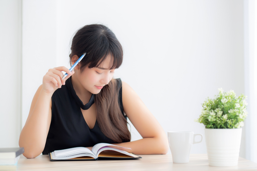 ノートを開き、ペンを手にして静かに考える女性