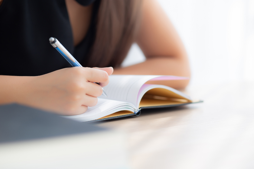ノートにペンで書き込みながら考えを整理している手元