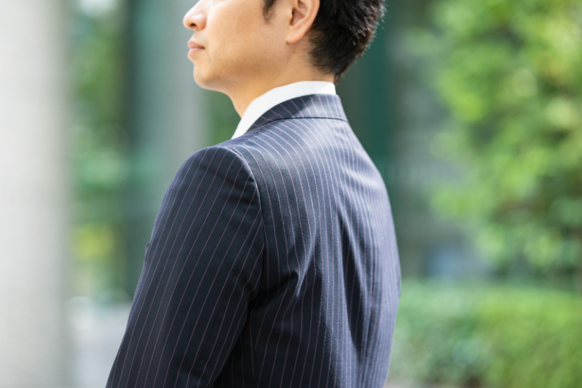 背景を振り返るように立つスーツ姿のビジネスパーソン