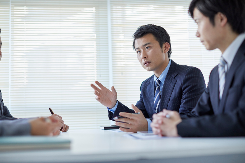 会議室で複数人が向き合い仕事の条件や進め方を話し合う様子