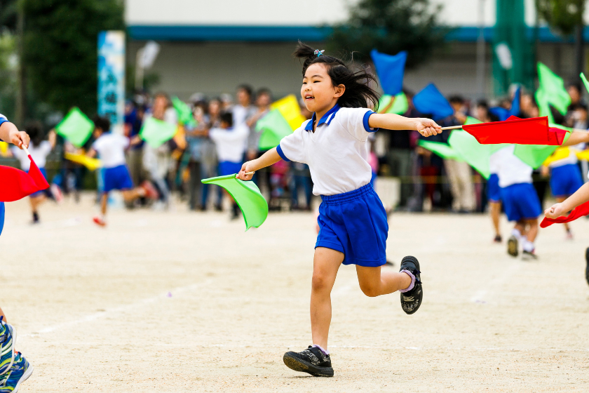 運動会で旗を持って走る子ども