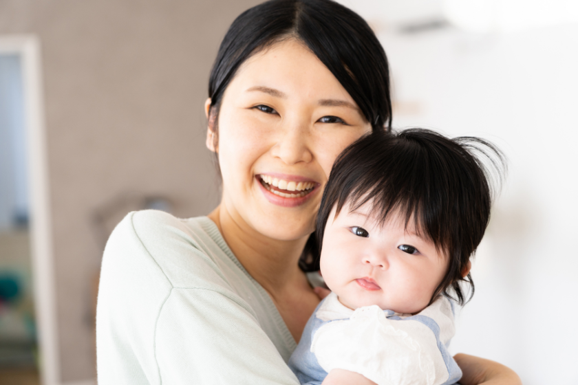 自宅で子どもを抱いて笑顔を見せる女性