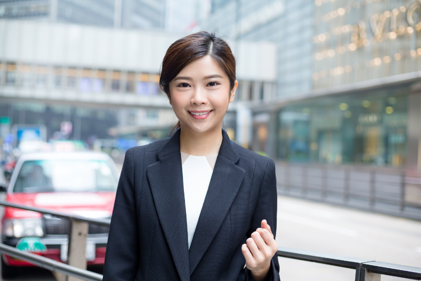 都市の街中で正面を向くスーツ姿の女性