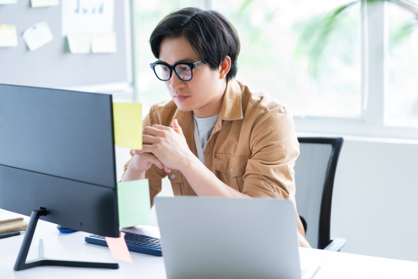 パソコン画面を見ながら、営業文や問い合わせ文の伝わり方を考えるビジネスパーソン