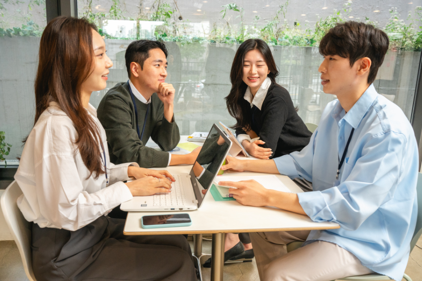 4人のビジネスメンバーがテーブルを囲み、掲載内容や実績の見せ方について意見を交わす様子